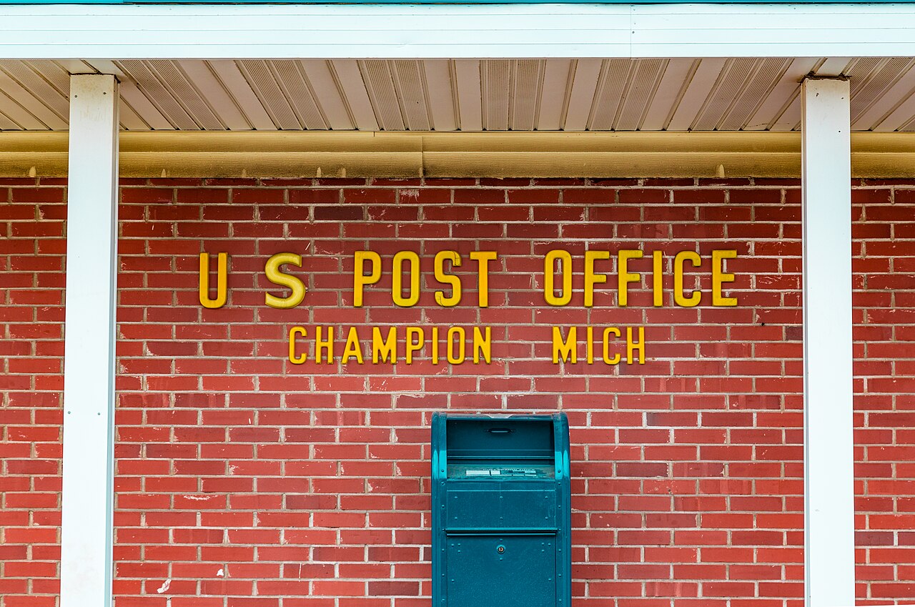 A blue U.S. Postal Service mail collection box outside a post office